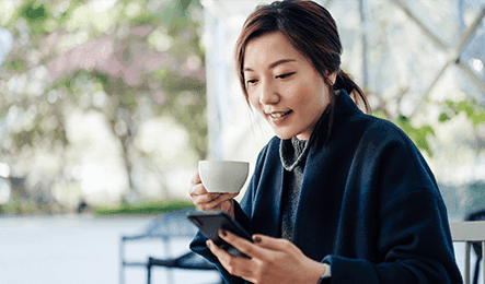 Woman with a cup looking at her mobile phone
