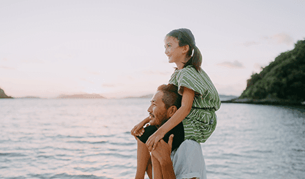 Dad with daughter on his shoulders at the beach